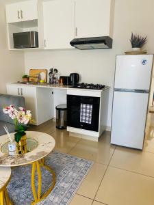 eine Küche mit einem weißen Kühlschrank und einem Tisch in der Unterkunft Cozy Mellenial Umhlanga studio in Durban