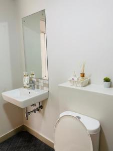 ein Bad mit einem Waschbecken und einem WC mit einem Spiegel in der Unterkunft Cozy Mellenial Umhlanga studio in Durban