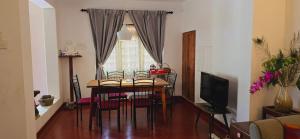 阿努拉德普勒Nature's Touch Villa的一间带桌椅和电视的餐厅