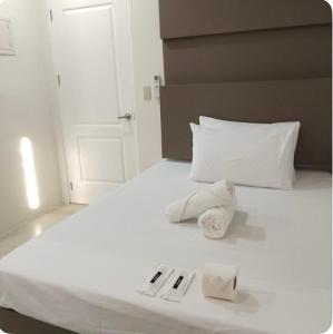 a white bed with two folded towels on it at Stay Inn Apartelle in Roxas City