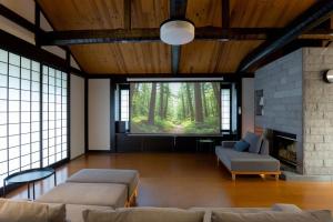 a living room with a couch and a big screen tv at Hakone Sengokuhara Soubokuan 箱根仙石原 相睦菴 in Sengokuhara