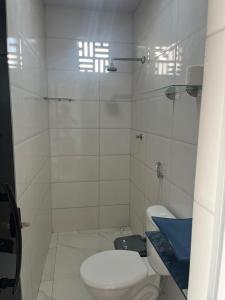 a white bathroom with a toilet and a shower at Hostel dos amigos in Salinópolis