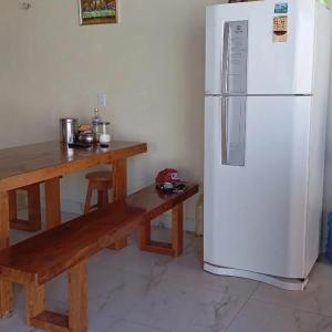 a kitchen with a white refrigerator and a wooden table at Hostel dos amigos in Salinópolis