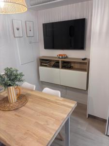 un salon avec une table et une télévision sur un mur dans l'établissement Plaza del Ayuntamiento -Centro Histórico-, à Oviedo