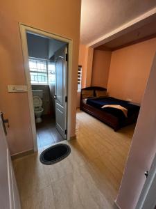 1 dormitorio con 1 cama y puerta al baño en Hideout nest, en Ooty