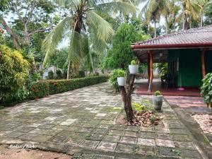 a walkway in front of a house with palm trees at Walawa cottage udawalawe in Udawalawe