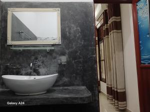 a bathroom with a sink and a tv on a wall at Walawa cottage udawalawe in Udawalawe