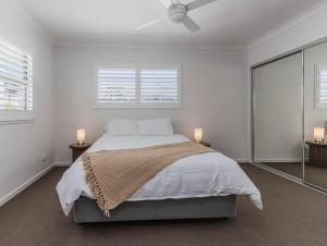 una camera da letto bianca con un letto e un ventilatore a soffitto di Dianella Dunes a Casuarina