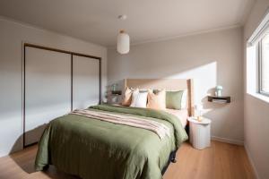 a bedroom with a large bed with a green blanket at Nelson Bridge House in Nelson