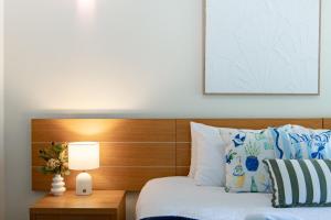 una camera da letto con letto con testata in legno e lampada di Amalfi Whitsunday Retreat Infinity Pool SeaViews ad Airlie Beach Altre 18 foto