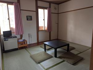 a living room with a table and two windows at Hachiko Inn in Myoko
