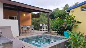a backyard with a swimming pool and a house at Rêve créole "villa Claire" mer plage mini piscine in Deshaies