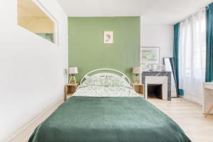 ein Schlafzimmer mit einem grünen Bett und einem Kamin in der Unterkunft L'élégance - La Petite Provence & La belle époque - hyper centre in Dreux