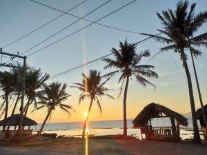 un grupo de palmeras en la playa al atardecer en Glenmark's Homestay New Oceanview Rooms, en Pagudpud 19 fotos más