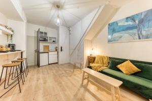 a living room with a green couch and a kitchen at L'élégance - La Petite Provence & La belle époque - hyper centre in Dreux