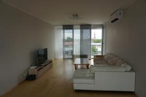 een woonkamer met een witte bank en een televisie bij Aida Marina Apartment in Pärnu