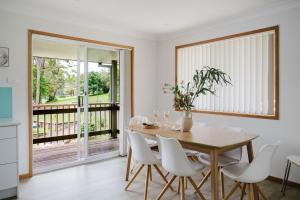 une salle à manger avec une table en bois et des chaises blanches dans l'établissement Paradise Lake, à Yatte Yattah