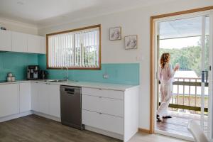 a woman standing in a kitchen looking out the window at Paradise Lake in Yatte Yattah +12 photos