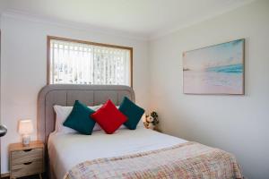 - une chambre avec un lit et des oreillers colorés dans l'établissement Paradise Lake, à Yatte Yattah