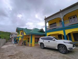 a white car parked in front of a row of houses at Glenmark's Homestay in Pagudpud +4 photos
