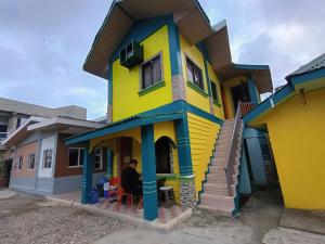 a person sitting in front of a colorful house at Glenmark's Homestay in Pagudpud