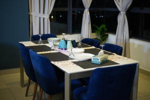 a table with blue chairs and a white table with food on it at Arte Plus Luxury Suites with KLCC View in Kuala Lumpur