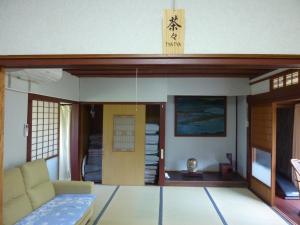 a living room with a couch and a door at ゲストハウス五郎平 in Nagahama