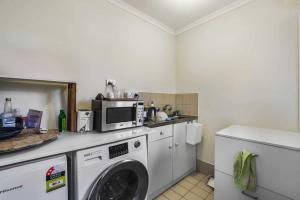 eine Küche mit Waschmaschine und Mikrowelle in der Unterkunft Unley rd parkside Adelaide in Unley