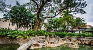 a park with a rock wall and trees and water at F1 Hotel Manila in Manila