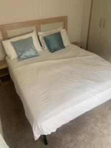 ein großes weißes Bett mit zwei blauen Kissen darauf in der Unterkunft Lovely 6 Berth Caravan With Free Wi-Fi At Harts Holiday Park, Kent Ref 74068W in Leysdown-on-Sea