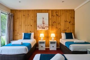 deux lits dans une chambre aux murs en bois dans l'établissement Sanctuary House Resort Motel, à Healesville 61 autres photos