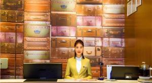 un homme debout devant un mur de valises dans l'établissement JTOUR Inn Wuzhou Arcade City Sanzongfu, à Wuzhou