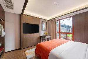 a bedroom with a bed and a flat screen tv at Xi'an Jinshengdi Hotel, Datang Everbright City, Big Wild Goose Pagoda Branch in Xi'an