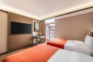 a hotel room with two beds and a flat screen tv at Xi'an Jinshengdi Hotel, Datang Everbright City, Big Wild Goose Pagoda Branch in Xi'an +26 photos