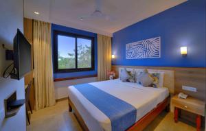 a bedroom with a large bed with a blue wall at Foxoso Sonnet, Anjuna Goa in Anjuna