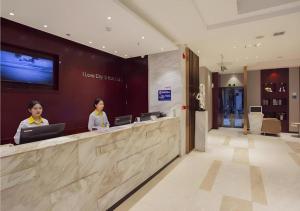 zwei Frauen sitzen an einem Tresen in einer Lobby in der Unterkunft City Comfort Inn Hechi Bama Shouxiang Avenue in Bama