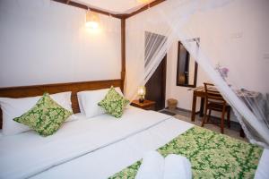 a bedroom with a white bed with green and white pillows at The Mud Crab 80 in Ahangama