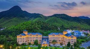 un grand bâtiment avec une montagne en arrière-plan dans l'établissement Deefly Yinrun Town Hotel, à Deqing