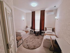 a small room with two beds and a window at Istiqlol Hotel in Namangan