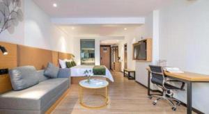 une chambre d'hôtel avec un lit, un canapé et un bureau dans l'établissement Green Tree Inn Guangxi Wuzhou 2nd Xinxing Road Liangguang Market, à Wuzhou