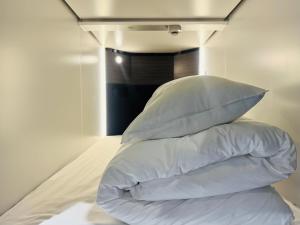una pila de almohadas encima de la cama en Capsule Hostel Beppu Tower, en Beppu 80 fotos más