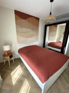 a bedroom with a red bed and a mirror at Charming 2-room apartment, Grand Annecy in Meythet