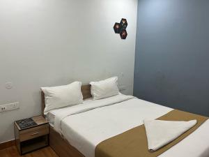 DispurTownhouse Lalmati National Highway 27 Formerly The Pinnacle Inn的卧室里有一张大床，床单和枕头都是白色的 更多12张照片