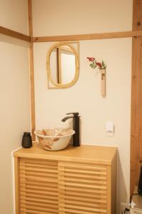 a bowl on top of a wooden cabinet with a mirror at Kimono Hotel Himeji 着物宿 in Himeji
