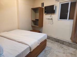 Un dormitorio pequeño con una cama y un televisor. en Hotel O Eleven, en Jabalpur