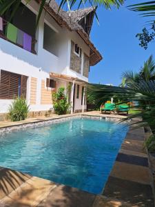 a swimming pool in front of a house at Diani Yoga Barn in Ukunda
