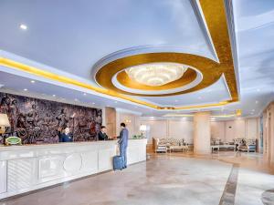 un homme debout au comptoir d'un hall d'hôtel dans l'établissement Vienna Hotel Shanghai Hongqiao National Exhibition Cente Sijing Metro Station, à Fenghuangshan