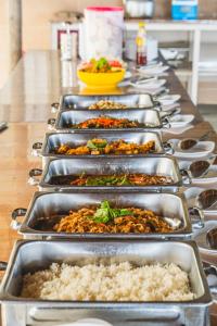 a row of metal trays of food on a table at Ara Dinawan Island Resort in Papar