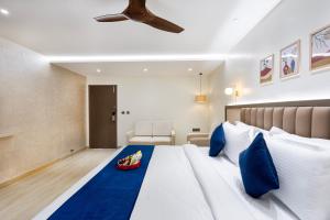 a bedroom with a large white bed with blue pillows at Regenta Z Sunrise Gachibowli, Hyderabad in Kondapur