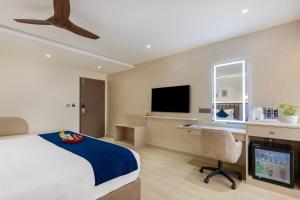 a bedroom with a bed and a desk and a television at Regenta Z Sunrise Gachibowli, Hyderabad in Kondapur